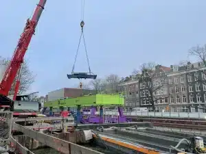 Een loopkat wordt op een portaalkraan gehesen met behulp van een mobiele kraan